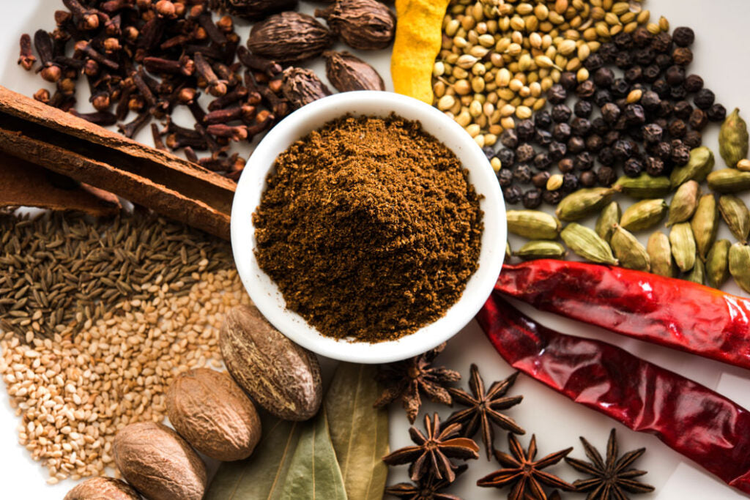 Spices around a bowl which has ground up spices. Attempted to show Sri Lankan Curry powders in the bowl.