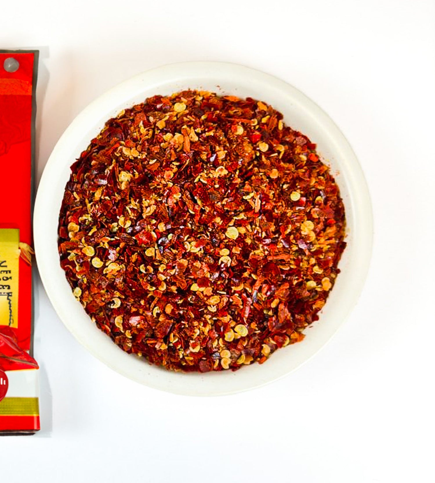 Red hot, chilli flakes from red chilli peppers, with seeds and no stems.